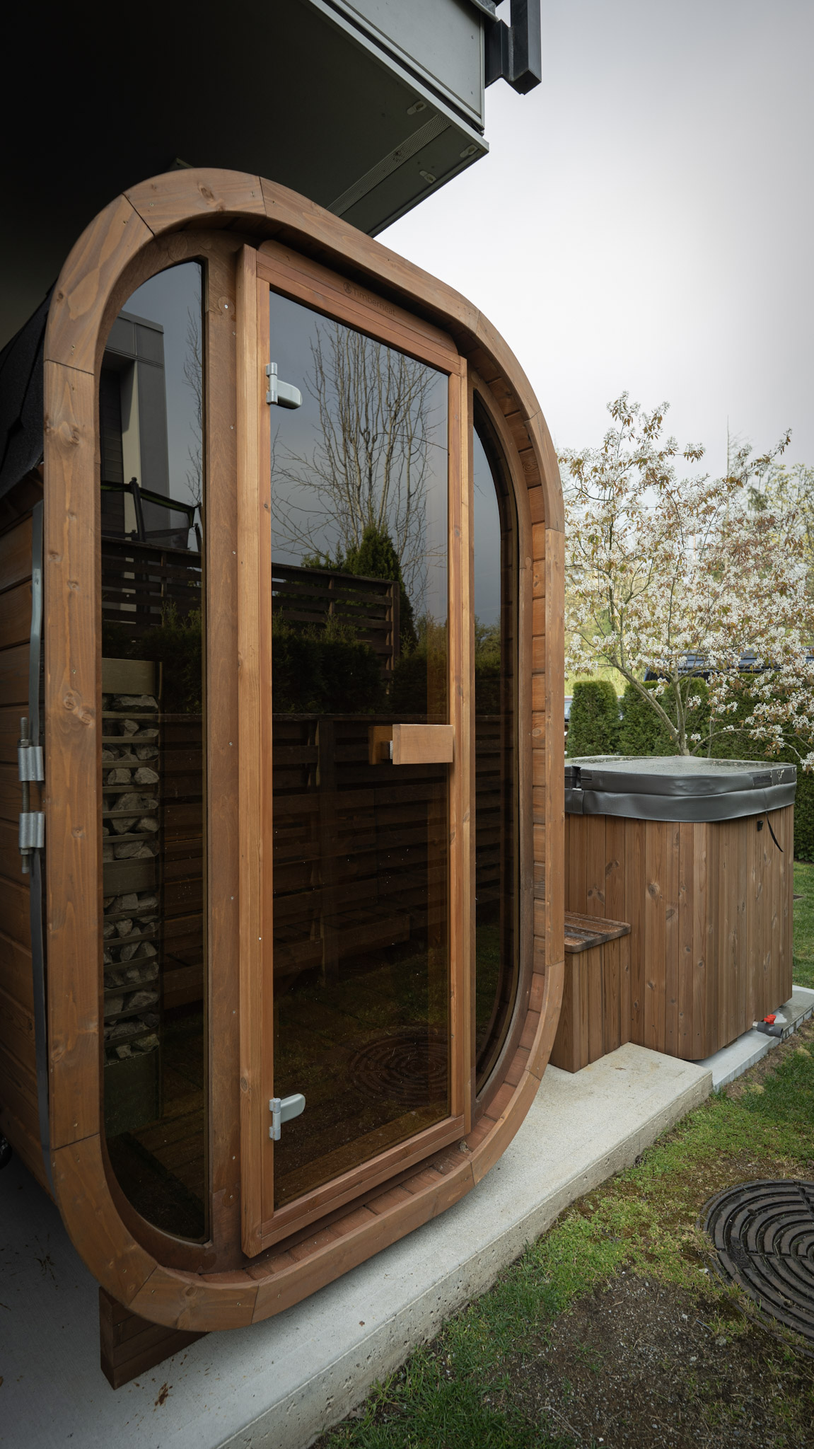 Minimalist wooden outdoor sauna in a dark forest setting with warm internal glow