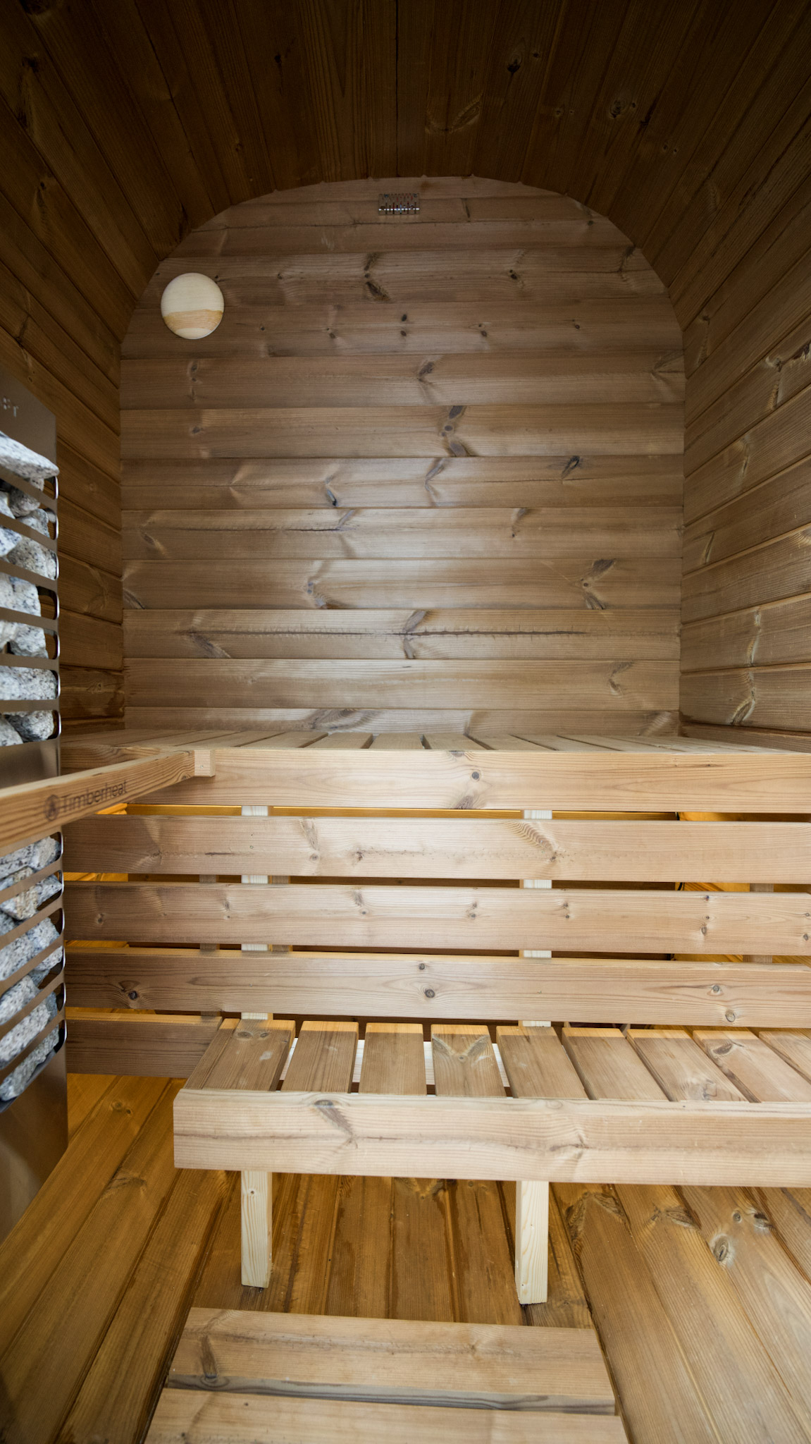 Close up of stainless steel hinges and thermally modified dark wood texture on a sauna door